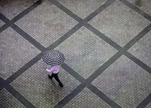 Office worker holding an umbrella walks out of a commercial building as it rains in Office worker holding an umbrella walks out of a commercial building as it rains in