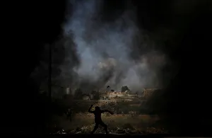 Palestinian demonstrator uses a sling to hurl stones at Israeli troops during a protest Palestinian demonstrator uses a sling to hurl stones at Israeli troops during a protest