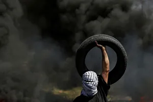 Palestinian protester carries a tire during clashes with Israeli troops near the Jewish Palestinian protester carries a tire during clashes with Israeli troops near the Jewish