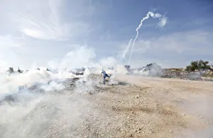 A Palestinian protester throws back a tear gas canister fired by Israeli troops during A Palestinian protester throws back a tear gas canister fired by Israeli troops during