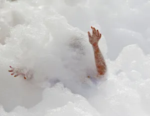 A participant runs through a foam bath during the Colour My Run charity fun run A participant runs through a foam bath during the Colour My Run charity fun run