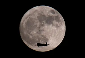 A passenger plane, with a supermoon full moon seen behind, makes its final landing A passenger plane, with a supermoon full moon seen behind, makes its final landing