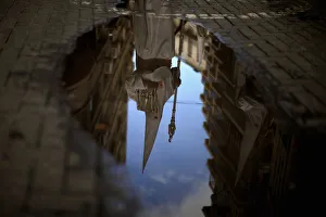 A penitent is reflected in a puddle of water after rain fell at the Humildad A penitent is reflected in a puddle of water after rain fell at the Humildad
