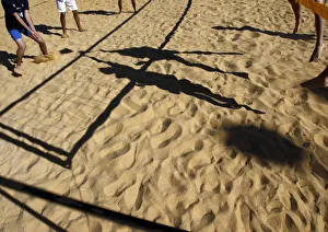 People cast shadows on the sand as they compete in a volleyball game in Jerusalem People cast shadows on the sand as they compete in a volleyball game in Jerusalem