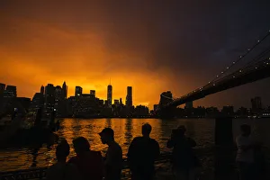People line a dock in Brooklyn to watch the sun set behind the Manhattan skyline after People line a dock in Brooklyn to watch the sun set behind the Manhattan skyline after