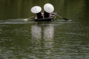 People protect themselves from the sun with parasols while rowing in Central Park People protect themselves from the sun with parasols while rowing in Central Park