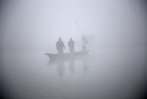 People ride on a boat to reach the bank of Rapti River during the foggy winter morning at People ride on a boat to reach the bank of Rapti River during the foggy winter morning at