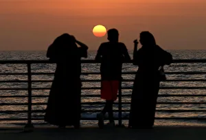 People stand on the corniche at sunset in Jeddah People stand on the corniche at sunset in Jeddah
