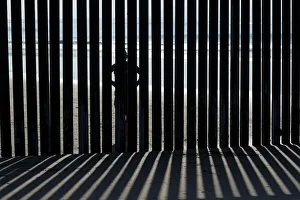 A person looks through the border wall towards the United States at Border Field State A person looks through the border wall towards the United States at Border Field State