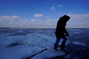 A person walks on fractured ice on the Wadden Sea during the low tide near the island of A person walks on fractured ice on the Wadden Sea during the low tide near the island of