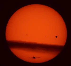A plane flies under a thin layer cloud crossing the sun as Venus (R A plane flies under a thin layer cloud crossing the sun as Venus (R