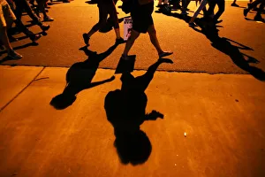 Protesters shadows mark the sidewalk as they march during another night of protests Protesters shadows mark the sidewalk as they march during another night of protests