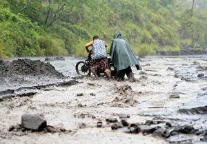 Residents push a motorcycle across a river mixed with lahar from Mount Mayon volcano in Residents push a motorcycle across a river mixed with lahar from Mount Mayon volcano in