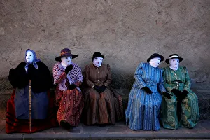 Revellers dressed as Mascaritas sit during carnival celebrations in the village of Revellers dressed as Mascaritas sit during carnival celebrations in the village of