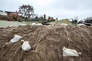 Sandbags and webbing are seen on a small hill in front of a house burned to the ground in Sandbags and webbing are seen on a small hill in front of a house burned to the ground in