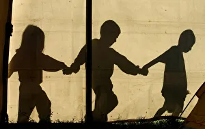 The shadows of children walking hand in hand are seen on a tent at a temporary refuge The shadows of children walking hand in hand are seen on a tent at a temporary refuge