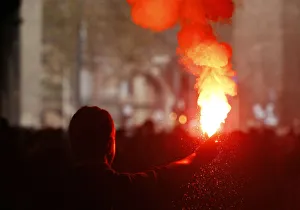 A student holds a lit flare during a demonstration in Rome A student holds a lit flare during a demonstration in Rome
