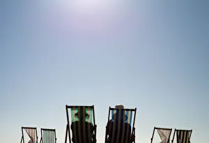 Sunbathers sit on deck chairs on Brighton beach, southern England Sunbathers sit on deck chairs on Brighton beach, southern England