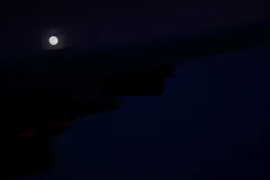A supermoon full moon can be seen in the distance over the wing of Air Force One A supermoon full moon can be seen in the distance over the wing of Air Force One