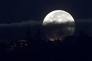 The supermoon is partly covered by clouds as it sets behind Wat Phrathat Doi Suthep in The supermoon is partly covered by clouds as it sets behind Wat Phrathat Doi Suthep in