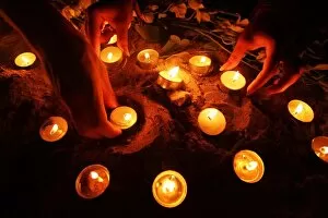 Images Dated 26th December 2005: Tourists arrange oil lamps during candle light vigil ceremony on Thai island of Phi Phi