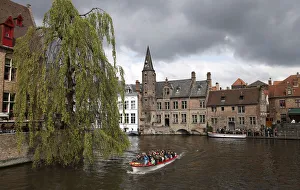 Tourists enjoy a boat ride on a canal of the old town in Bruges Tourists enjoy a boat ride on a canal of the old town in Bruges