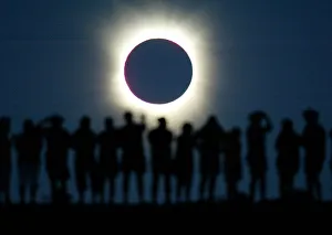 Tourists watch the sun being blocked by the moon during a solar eclipse in the Australian Tourists watch the sun being blocked by the moon during a solar eclipse in the Australian