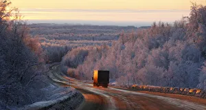Vehicles drive during sunrise in the Taiga area along the M54 highway Krasnoyarsk Vehicles drive during sunrise in the Taiga area along the M54 highway Krasnoyarsk