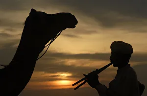 Villager plays flute as he is silhouetted against the setting sun over the Thar Desert Villager plays flute as he is silhouetted against the setting sun over the Thar Desert
