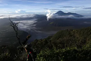A visitor walks as Indonesias Mount Bromo volcano spew smoke next to Mount Semeru A visitor walks as Indonesias Mount Bromo volcano spew smoke next to Mount Semeru