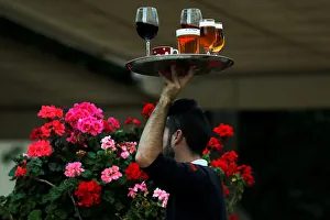 A waiter carries a tray with drinks at the terrace of a restaurant in downtown Malaga A waiter carries a tray with drinks at the terrace of a restaurant in downtown Malaga