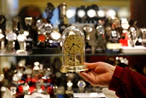 A watchmaker holds a clock in his store in Vienna A watchmaker holds a clock in his store in Vienna