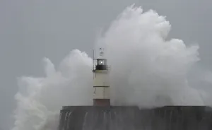 Waves crash against the harbour wall and light beacon at Newhaven in southern England Waves crash against the harbour wall and light beacon at Newhaven in southern England