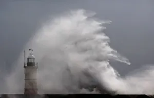 Waves crash against the lighthouse and sea wall during high winds Waves crash against the lighthouse and sea wall during high winds