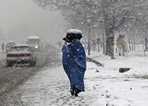 A woman carries a sack on her head along a street on a snowy day in Kabul A woman carries a sack on her head along a street on a snowy day in Kabul