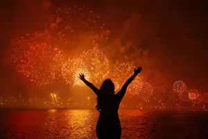 A woman celebrates the New Year as she watches fireworks exploding above Copacabana beach A woman celebrates the New Year as she watches fireworks exploding above Copacabana beach