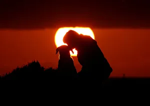 A woman gives her dog a kiss as they watch the sunset at Anchor Bay outside Mellieha A woman gives her dog a kiss as they watch the sunset at Anchor Bay outside Mellieha