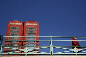 A woman stands next to two traditional telephone boxes in Brighton A woman stands next to two traditional telephone boxes in Brighton