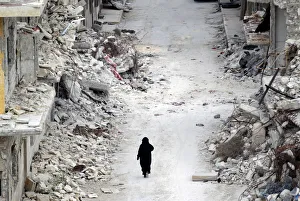 A woman walks past damaged buildings in the rebel-controlled area of Maaret al-Numan town A woman walks past damaged buildings in the rebel-controlled area of Maaret al-Numan town