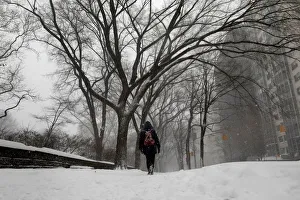 A woman walks in the snow next to Central Park along 5th avenue in upper Manhattan during A woman walks in the snow next to Central Park along 5th avenue in upper Manhattan during