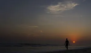 A woman walks during sunset on Barra da Tijuca beach in Rio de Janeiro A woman walks during sunset on Barra da Tijuca beach in Rio de Janeiro