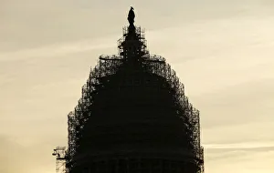 A worker reaches for supplies while working atop the scaffolded dome of the U.S A worker reaches for supplies while working atop the scaffolded dome of the U.S