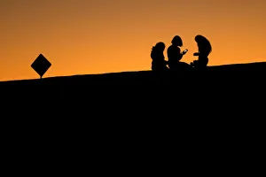 Young girls look at their phones as they sit on a hillside after sun set in El Paso Young girls look at their phones as they sit on a hillside after sun set in El Paso