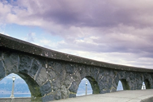 An arched stone rock wall frames three light posts overlooking the Columbia River An arched stone rock wall frames three light posts overlooking the Columbia River