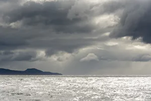 Australia, Tasmania, Tasman Sea. Dramatic line of sun on horizon through storm clouds Australia, Tasmania, Tasman Sea. Dramatic line of sun on horizon through storm clouds