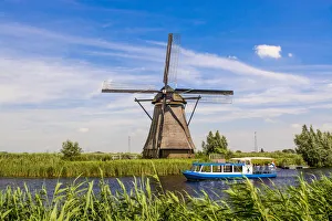 Canal tour boat and windmill in Unesco World Heritage Site, Kinderdijk, Holland Canal tour boat and windmill in Unesco World Heritage Site, Kinderdijk, Holland