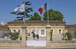 Chateau La Couspaude, the main building, with a white iron fence a French flag Chateau La Couspaude, the main building, with a white iron fence a French flag