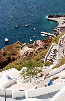 Along the cliff of Oia, view the boats docked in the water, Greece Along the cliff of Oia, view the boats docked in the water, Greece