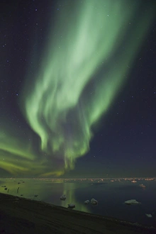 Curtains of Aurora Borealis are reflected in a perfectly calm Arctic Ocean, dotted Curtains of Aurora Borealis are reflected in a perfectly calm Arctic Ocean, dotted