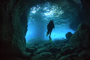 Diver swimming through a sea cave near Poor Knights Islands, North Island, New Zealand Diver swimming through a sea cave near Poor Knights Islands, North Island, New Zealand